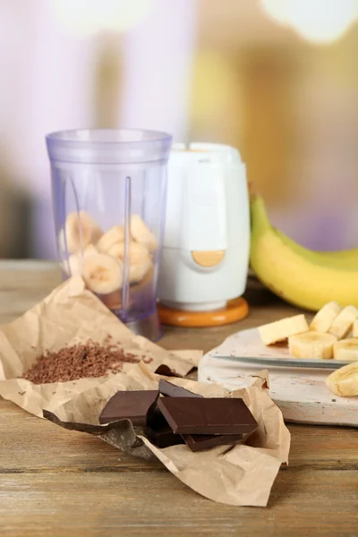 Plátano en rodajas sobre tabla de cortar y chocolate picado, sobre mesa de madera, sobre fondo brillante — Foto de Stock