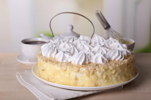 Smakelijk zelfgemaakte meringue taart en kopje thee op houten tafel, op lichte achtergrond — Stockfoto