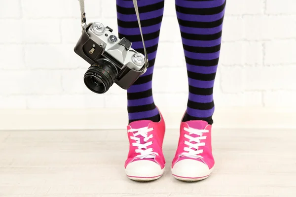 Ragazza in scarpe da ginnastica con fotocamera retrò in camera — Foto Stock