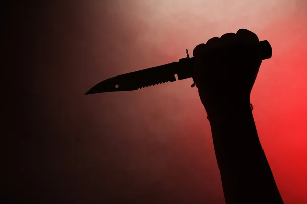 Mão feminina segurando faca no fundo vermelho — Fotografia de Stock