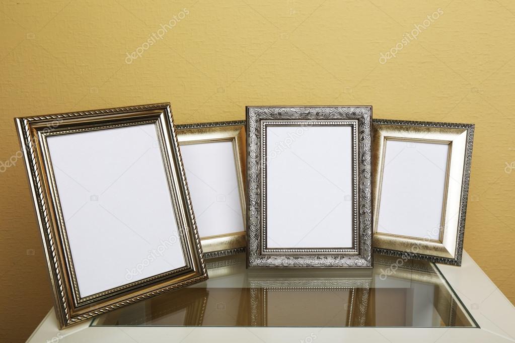 Vintage photo frames on coffee table on wallpaper background