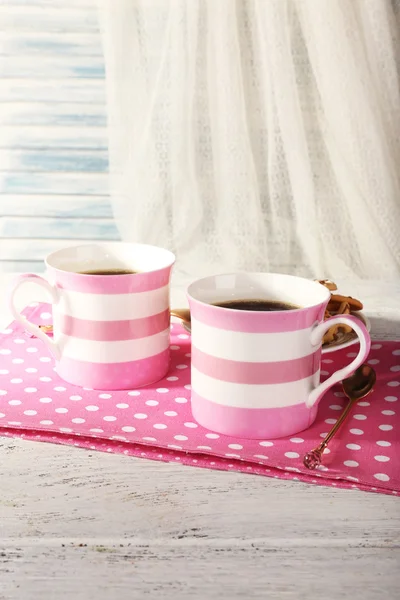 Two mugs of coffee on napkin on table on white curtain background — Stock Photo, Image