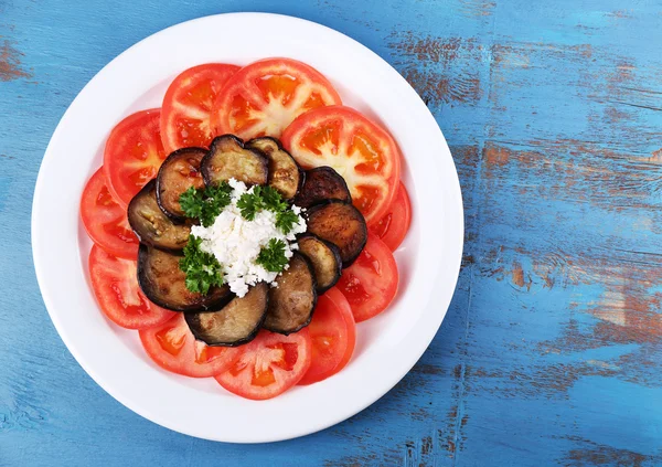 Eggplant salad with tomatoes and feta cheese, on wooden background — Stock Photo, Image