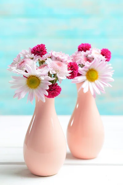 Vackra blommor i vaser på bordet på ljusblå bakgrund — Stockfoto