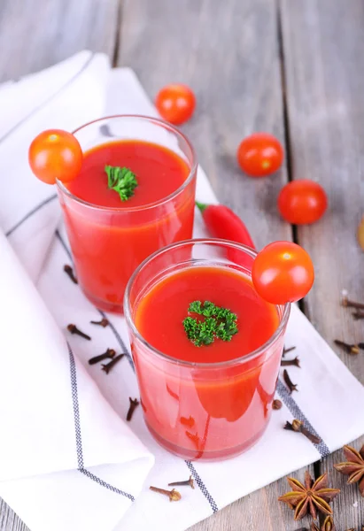 Jugo de tomate en vasos y verduras frescas en servilleta sobre fondo de madera — Foto de Stock