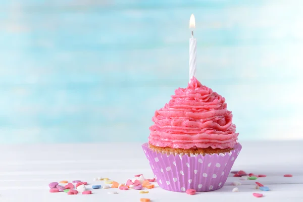 Delicioso cupcake de aniversário na mesa no fundo azul claro — Fotografia de Stock