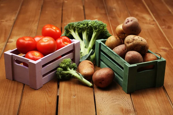 Различные овощи в коробках на деревянном фоне — стоковое фото