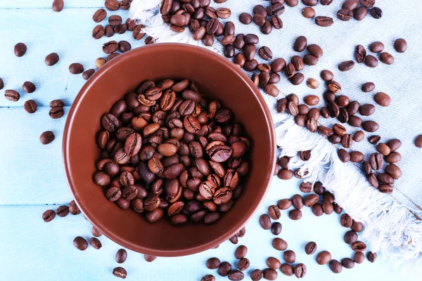Kom gemalen koffie en koffiebonen op blauwe houten achtergrond met jeans materiaal — Stockfoto