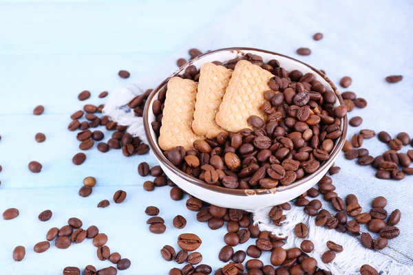 Kom shortbread koekjes en koffie bonen op blauwe houten achtergrond met jeans materiaal — Stockfoto
