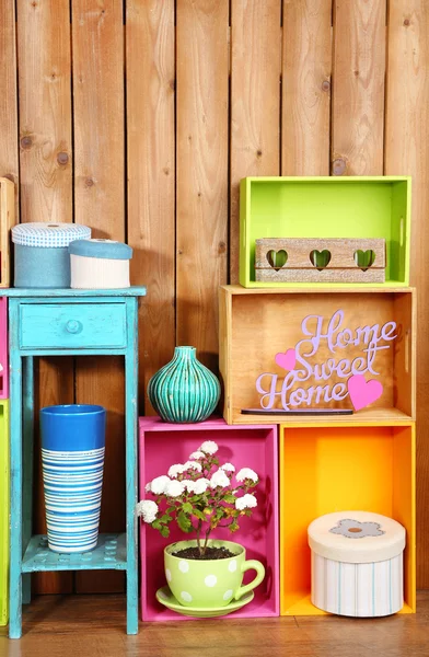 Beautiful colorful shelves with different home related objects on wooden wall background — Stock Photo, Image