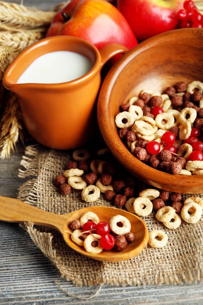 Verschiedene süße Müslis in Schale, Früchte und Krug mit Milch auf Serviette, auf farbigem Holzgrund — Stockfoto