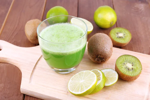 Glas vers limoensap met stukken van kalk en kiwi op gesneden bestuur en houten tafel achtergrond — Stockfoto