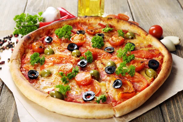 Ízletes pizza kolbásszal, zöldségek és chili paprika, a fából készült asztal háttere — Stock Fotó