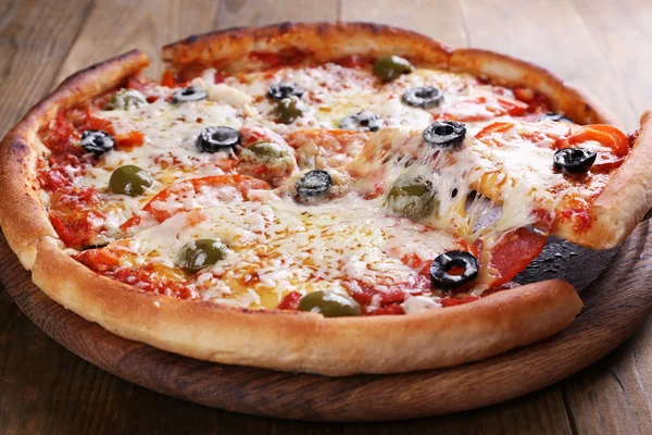 Pizza com queijo a bordo e fundo de mesa de madeira — Fotografia de Stock