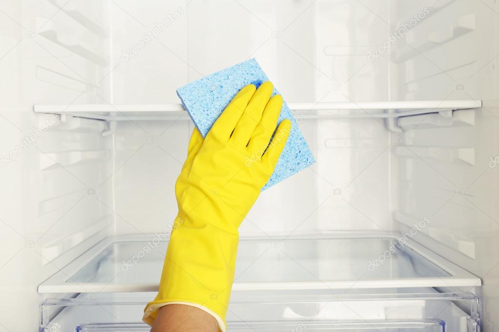 Woman's hand washing refrigerator with duster