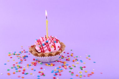 Doğum günü kek mum ve mor arka plan üzerinde renkli parıldıyor