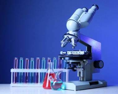 Mikroskop ve masaya renk arka plan üzerinde test tüpleri