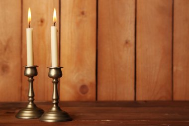 Retro candlesticks with candles on wooden background clipart