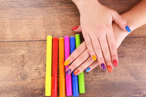 Multicolor female manicure with markers on wooden background — Stock Photo, Image