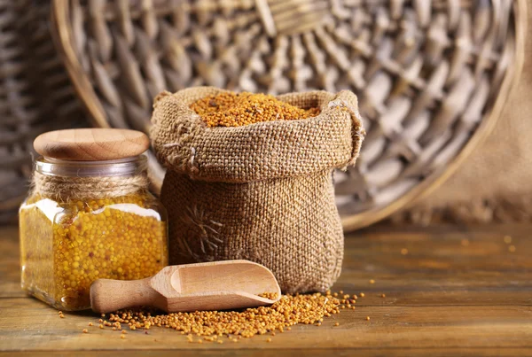 Mustard seeds in bag and Dijon mustard in glass jar on wooden background — Stock Photo, Image