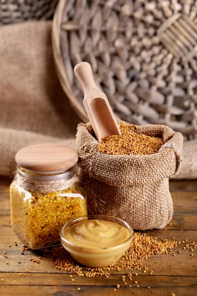 Mustard seeds in bag and sauce in sauce-boat on  wooden background — Stock Photo, Image