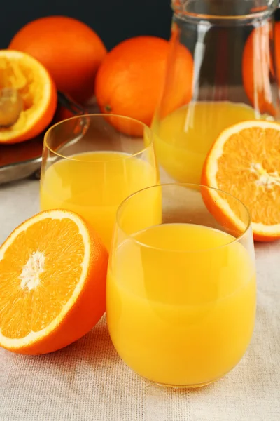 Copo de suco de laranja com fatias em fundo de toalha de mesa — Fotografia de Stock