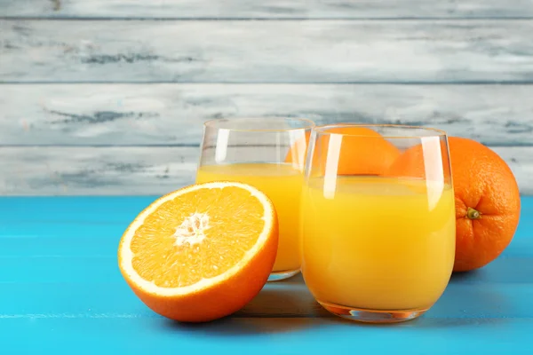 Glas Orangensaft auf farbigem Holzhintergrund — Stockfoto