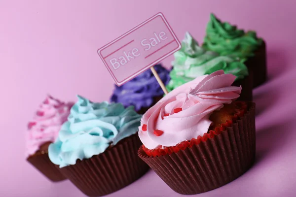 Delicious cupcakes with inscription on color background — Stock Photo, Image