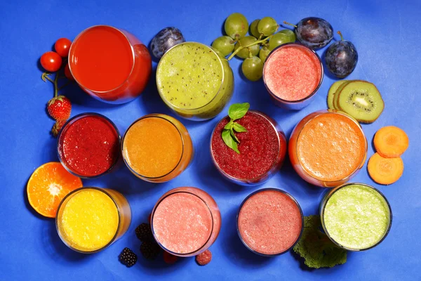 Glasses of tasty fresh juice, on blue background — Stock Photo, Image