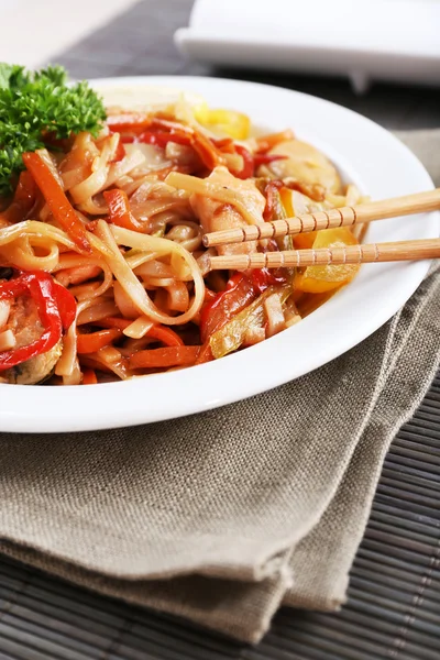 Fideos chinos con verduras y mariscos en plato sobre fondo de estera de bambú —  Fotos de Stock