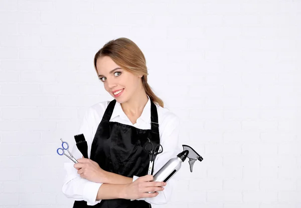 Beautiful girl hairdresser on light background — Stock Photo, Image