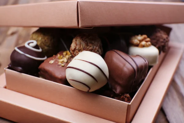 木製の素朴な背景の上にチョコレートでいっぱいのボックス — ストック写真