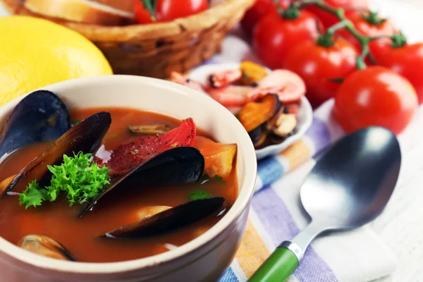 Tasty soup with shrimps, mussels, tomatoes and black olives in bowl on wooden background — Stock Photo, Image