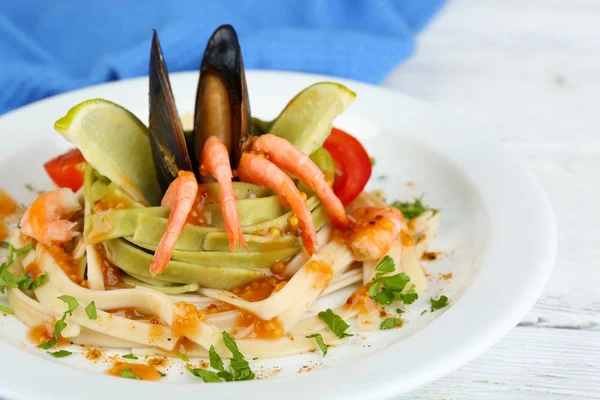 Tasty pasta with shrimps, mussels and tomatoes on plate on wooden background — Stock Photo, Image