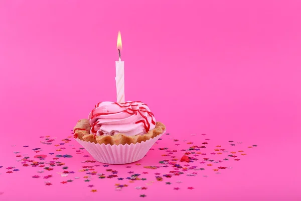 Birthday cup cake with candle and colorful stars on pink background — Stock Photo, Image