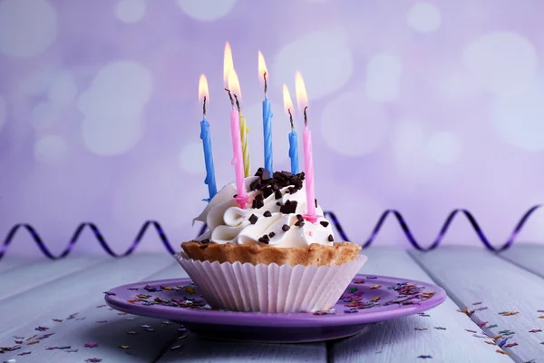 Birthday cup cake with candles on plate on wooden table and light background — Stock Photo, Image