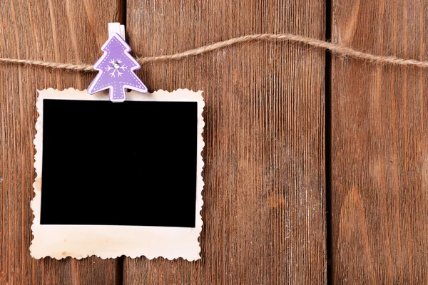 Moldura de foto em branco e decoração de Natal na corda, no fundo de madeira — Fotografia de Stock