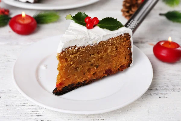 Slice of cake covered cream with Christmas decoration on table, on wooden wall background — Stock Photo, Image