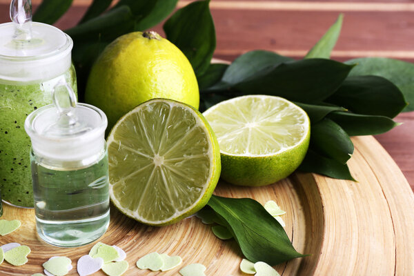 Spa composition with lime on wooden plate and wooden table background