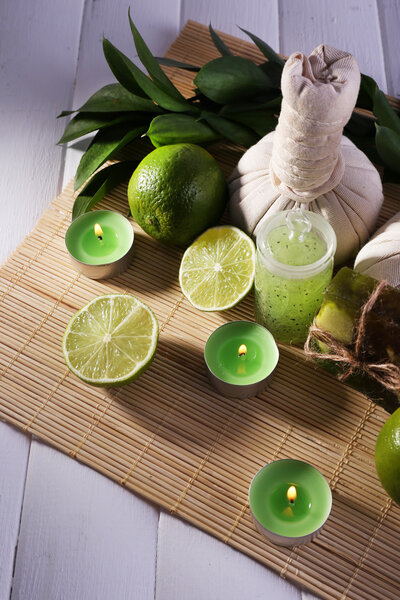 Spa composition with lime and compress balls on bamboo mat and color wooden background