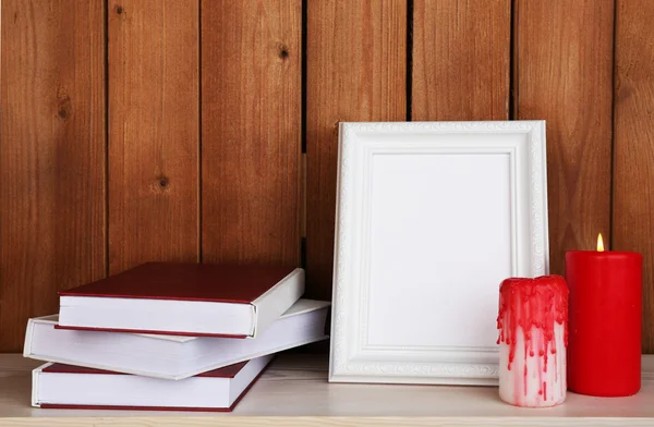 Fotolijsten met kaarsen en boeken op houten oppervlak en een houten muur achtergrond — Stockfoto