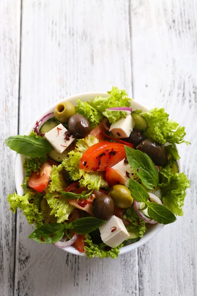 Greek salad in plate on color wooden table background — Stock Photo, Image