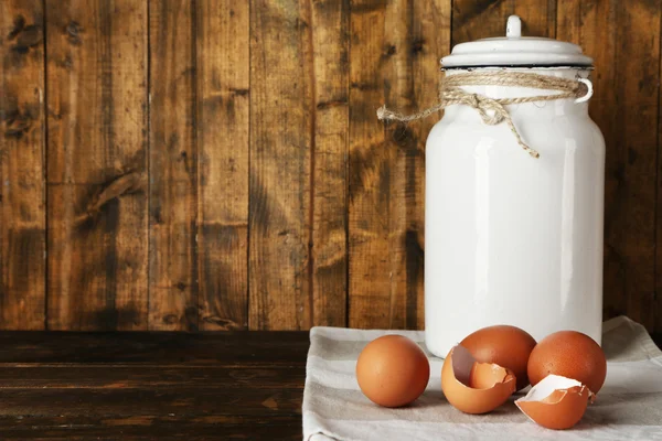 Melk kan met eieren en de "eggshell" op rustieke houten achtergrond — Stockfoto