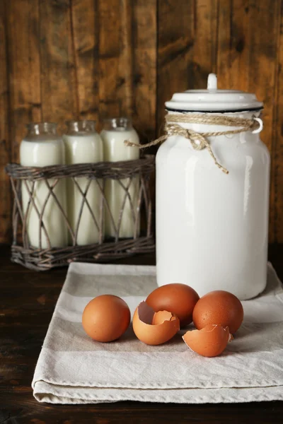 Milk can with eggs, eggshell and  glass bottles on rustic wooden background — Stock Photo, Image