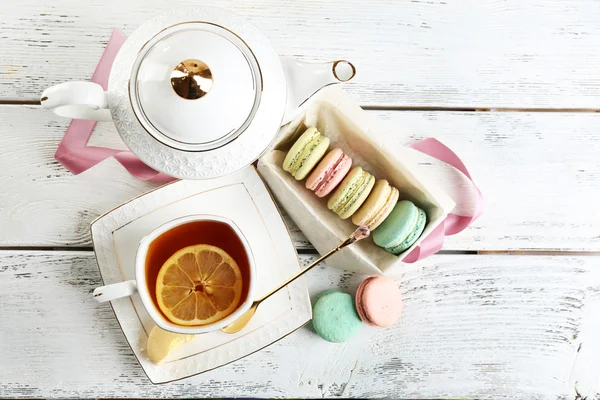 Macaroni colorati con tazza di tè su sfondo di legno — Foto Stock