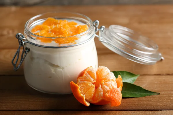 Dessert au lait savoureux avec des morceaux de mandarine frais dans un bocal en verre, sur fond de bois — Photo