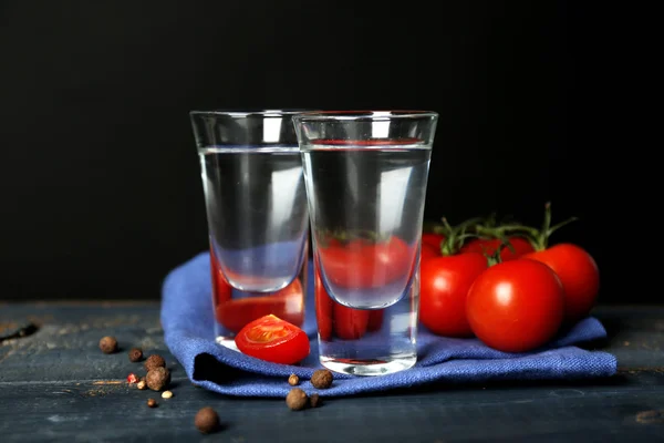 Okulary z ouzo i pomidory na drewnianym stole, na szarym tle — Zdjęcie stockowe