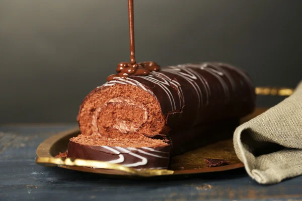 Délicieux gâteau roulé sur table en bois, sur fond sombre — Photo