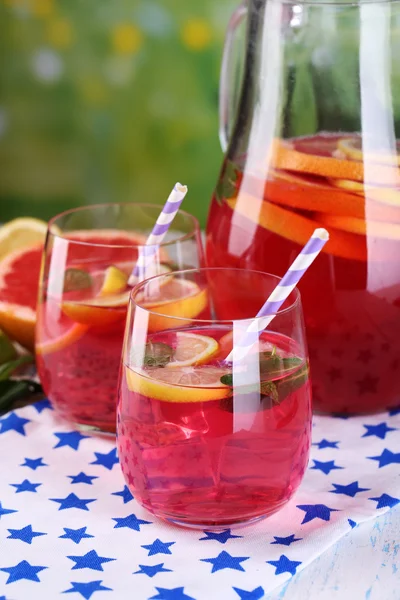 Rosa Limonade in Gläsern und Krug auf dem Tisch vor natürlichem Hintergrund — Stockfoto