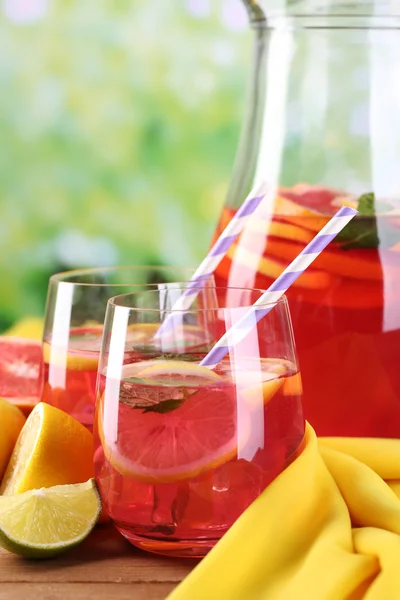 Limonada rosa em copos e jarro na mesa sobre fundo natural — Fotografia de Stock